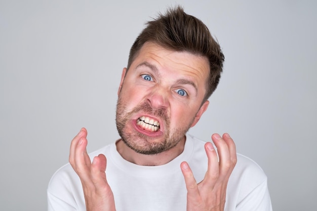 Handsome man angry shouts insulting someone with cruel words