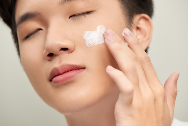 Handsome man applying eye cream