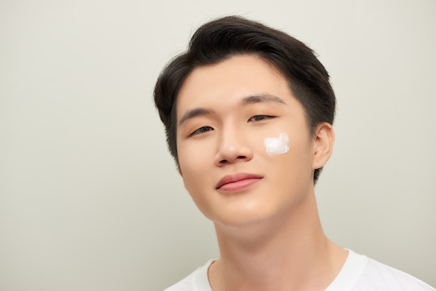 Handsome man applying eye cream