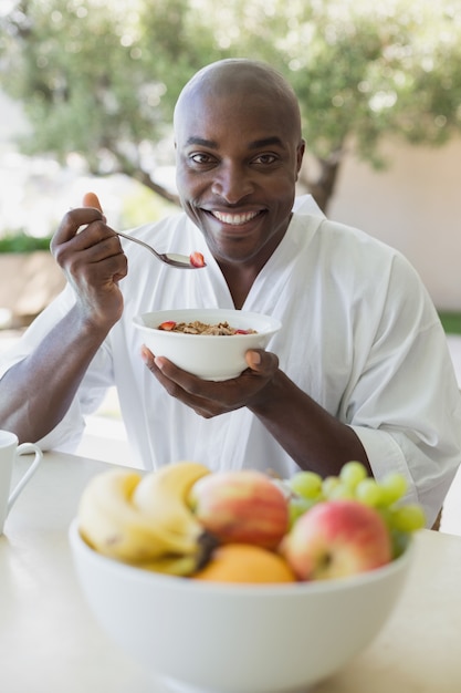 Handsome man in bathrobe having breakfast outside