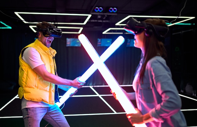 Handsome man and beautiful young woman with glasses of virtual reality. VR, games, entertainment, future technology concept. Couple with virtual reality headset having fun together.