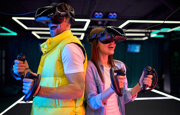 Handsome man and beautiful young woman with glasses of virtual reality. VR, games, entertainment, future technology concept. Couple with virtual reality headset having fun together.