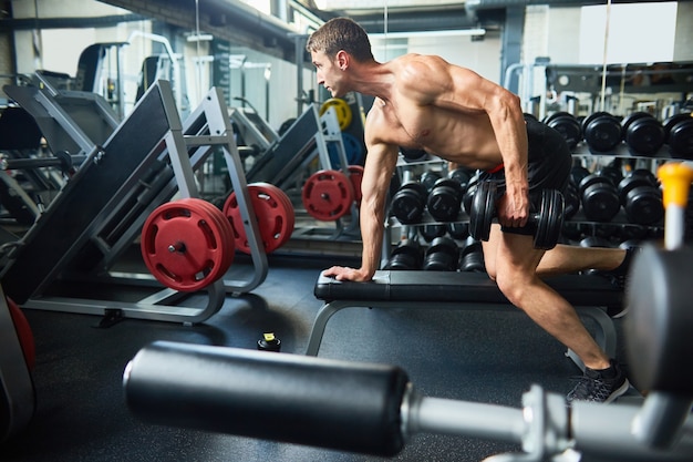 Handsome Man Building Muscles in Gym