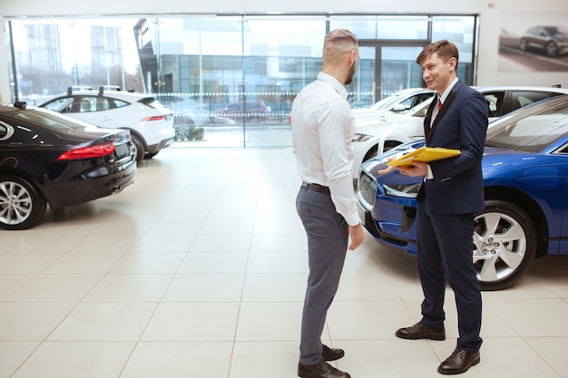 Handsome man buying new car at the dealership