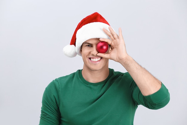 Handsome man in Christmas hat holding bauble