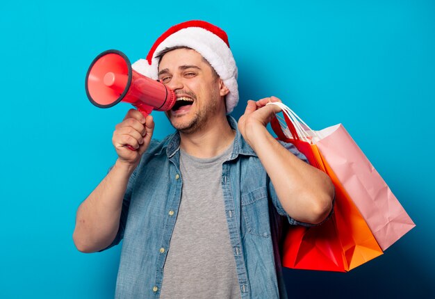 Handsome man in Christmas hat with loud-hailer and shopping bags