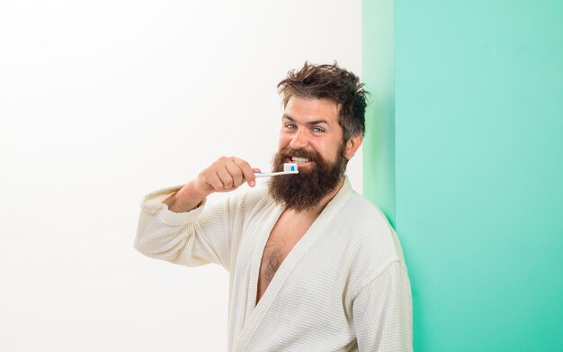 Handsome man cleaning teeth in bathroom oral care bearded man brushing teeth with toothbrush dental