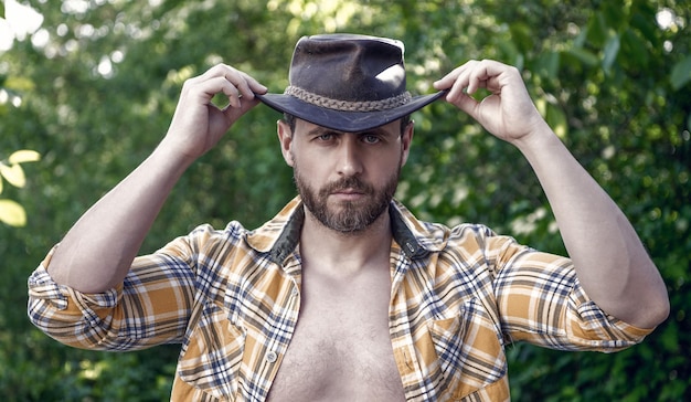 Handsome man in cowboy hat sexy cowboy in checkered shirt western cowboy wearing hat