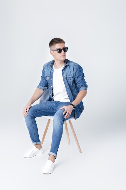 Handsome man in denim sits on chair