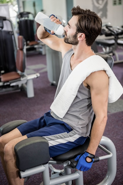 Handsome man drinking water at the gym