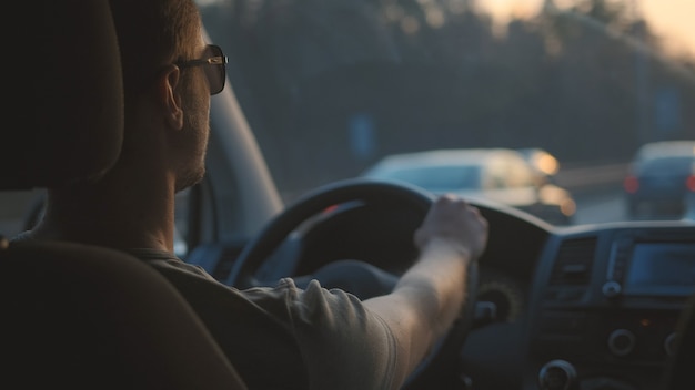 The handsome man drives the car along the highway