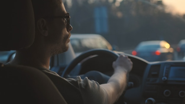 The handsome man drives the car along the highway