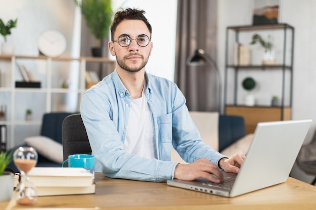 Handsome man in eyeglasses sitting at desk with laptop