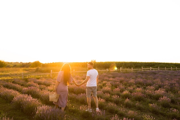 Handsome man gently hugging pretty woman with picnic basket spending weekend outdoors concept