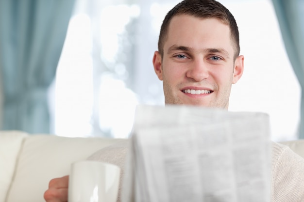 Handsome man having a coffee while reading the news