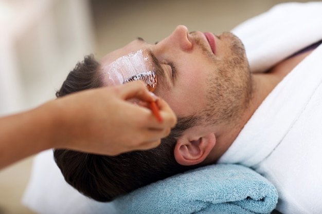 handsome man having facial in spa salon