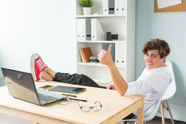 Handsome man having fun, sitting at the table with foot on it