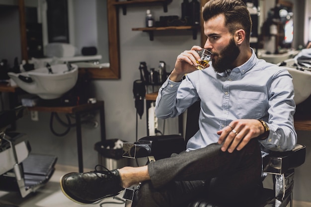 Handsome man having liquor in barbershop