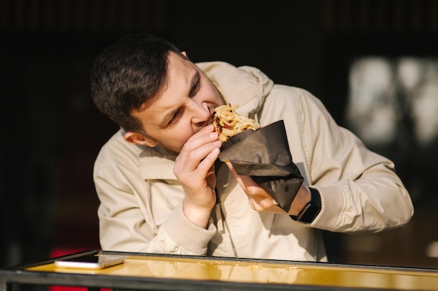 Handsome man having traditional hot dog cuisine during rest break caucasian guy enjoying street