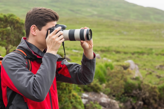 Handsome man on a hike taking a photograph