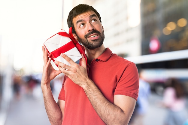 Handsome man holding a gift on unfocused background