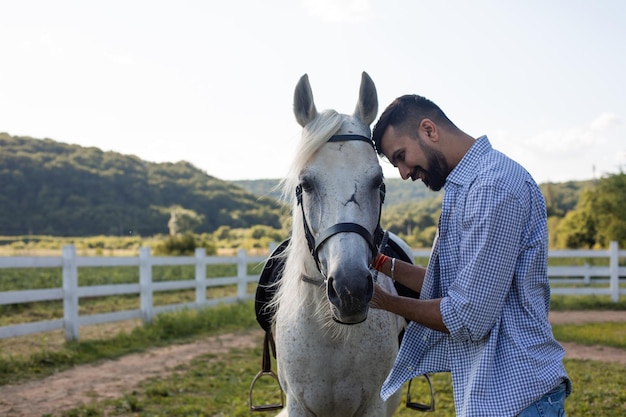 The handsome man is looking into the eyes of a horse