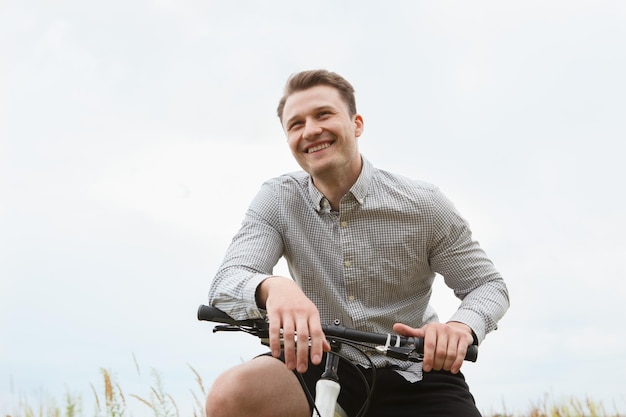 Handsome man is smiling while cycling in the field