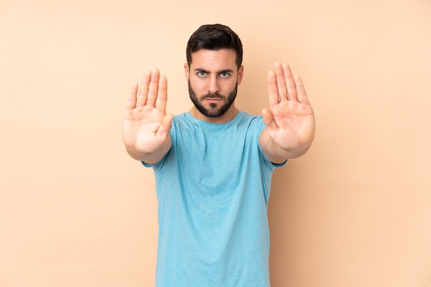 handsome man isolated on beige making stop gesture and disappointed