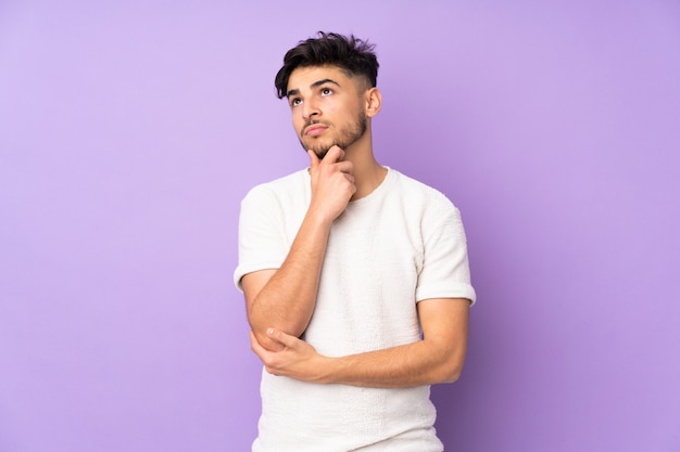 Handsome man over isolated wall having doubts