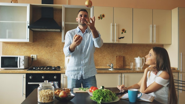 Handsome man juggle with apples to impress his girlfriend