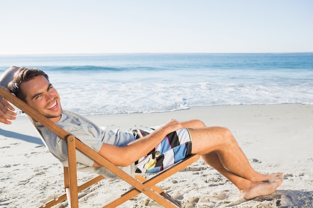 Handsome man lying on his deck chair smiling at camera