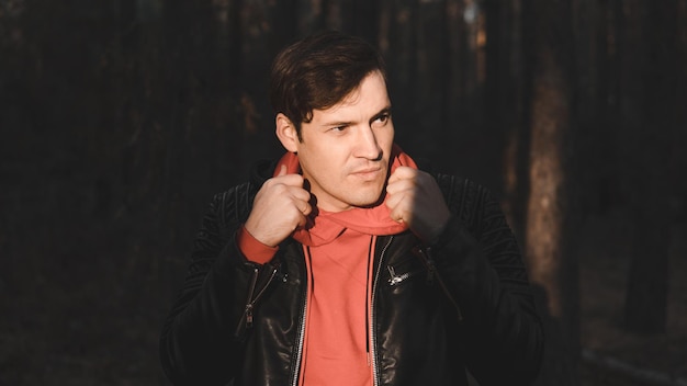 A handsome man posing at night in the autumn forest Male in warm casual clothes standing in the Park