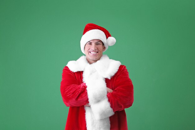 Handsome man in Santa Claus costume on color background