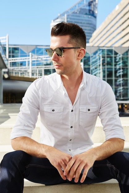 Handsome man sitting in city with sunglasses 