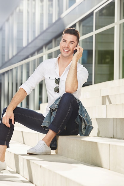 Handsome man sitting outside talking on mobile phone