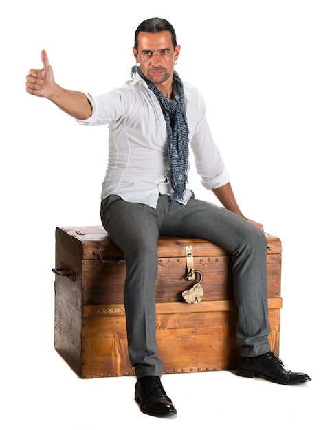 Handsome man sitting on a wooden chest and showing ok sign