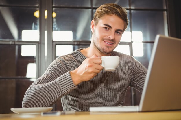 Handsome man smiling and drinking coffee