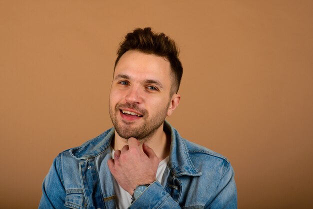 Handsome man standing and smiling isolated on the light brown studio background.