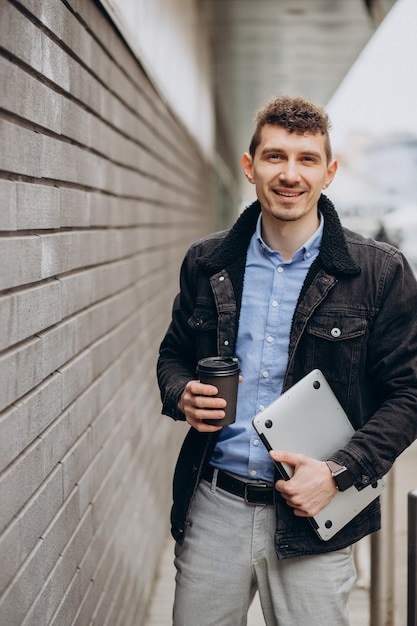 Handsome man standing in the street and holding laptop