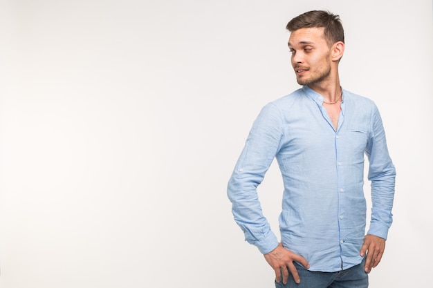 Handsome man standing and watching on empty place over the white surface