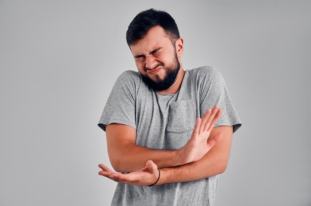 Handsome man suffering from pain, on gray background. Pain concept.