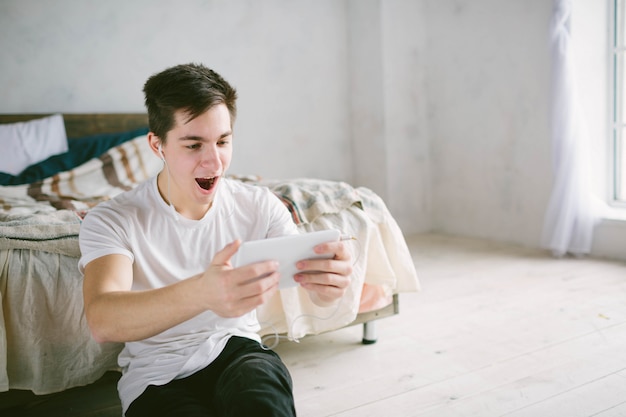 Handsome man surfing on tablet. Guy talking with friends, video conference, skype, tablet. The young student scrolls social networks