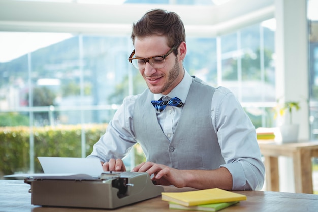 Handsome man using old fashioned typewriter in bright office