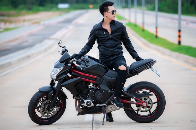 Handsome man wear black leather for driver on the wayPicture of asian Guy biker with motorcycle on the roadThailand peple