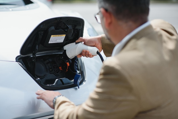 Handsome man while charging electric car