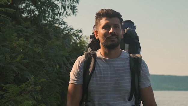 The handsome man with backpack walking along the coast