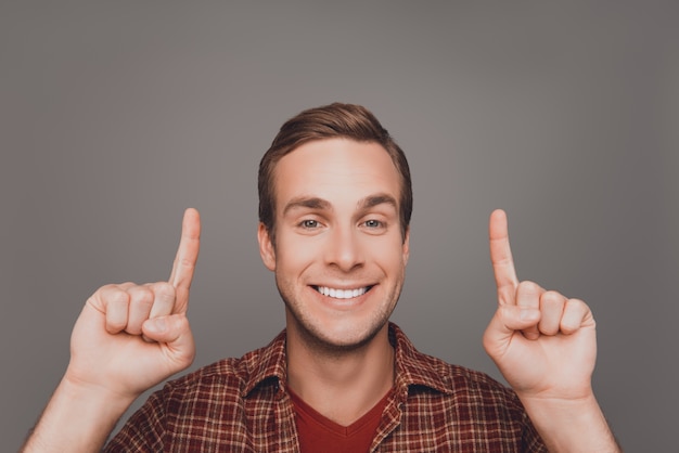 Handsome man with beaming smile gesturing with fingers under head