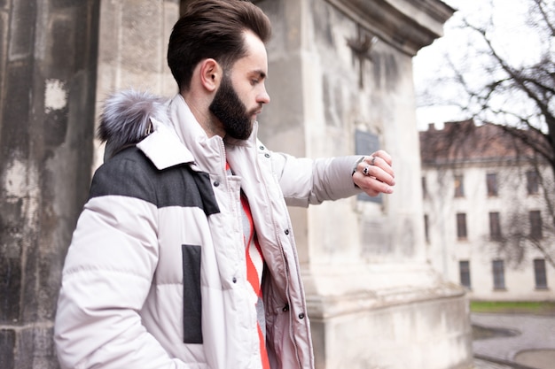 Handsome man with a beard looks at his watch