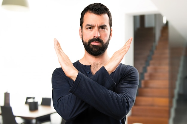 Handsome man with beard making NO gesture inside house