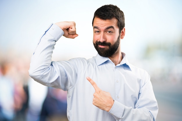 Handsome man with beard making strong gesture on unfocused background